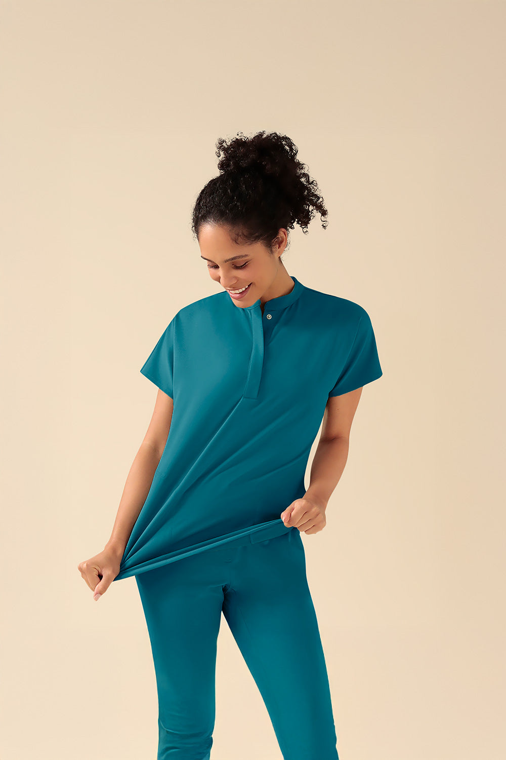 KAERE Schlupfkasack in Petrol, Damen-Model reißt am Schlupfasack mit Stehkragen und den Stretch-Effekt zu unterstreichen.